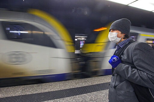 A man wearing a protective mask waits for a train at the nearly empty Central station in Brussels, Monday, March 16, 2020. Belgium has closed schools, restaurants and bars as well as cancelled cultural and sporting events in an effort to stem the spread of the coronavirus. For most people, the coronavirus causes only mild or moderate symptoms, such as fever and cough. For some, especially older adults and people with existing health problems, it can cause more severe illness, including pneumonia. (AP Photo/Olivier Matthys)