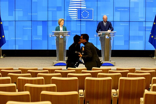 Photographers move around in a nearly empty press room as European Council President Charles Michel, right, and European Commission President Ursula von der Leyen, left, speak after a video-conference with G7 leaders at the European Council building in Brussels, Monday, March 16, 2020. European Commission President Ursula von der Leyen wants the European Union to put in place a 30-day ban on people entering the bloc for non-essential travel reasons in an effort to curb the spread of coronavirus. For most people, the new coronavirus causes only mild or moderate symptoms, such as fever and cough. For some, especially older adults and people with existing health problems, it can cause more severe illness, including pneumonia. (AP Photo/Olivier Matthys)