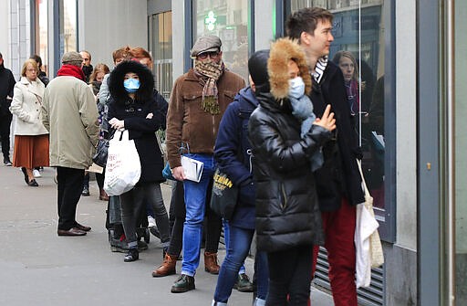 People with a protective masks line up at a supermarket in Paris, Monday, March 16, 2020. France's government announced Saturday closing restaurants, bars and other establishments to limit the spread of the new coronavirus. For most people, the new coronavirus causes only mild or moderate symptoms, such as fever and cough. For some, especially older adults and people with existing health problems, it can cause more severe illness, including pneumonia. (AP Photo/Michel Euler)