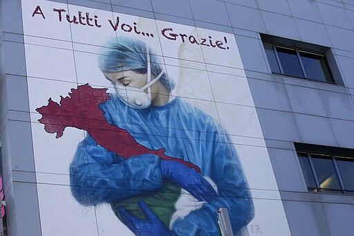 A giant graffiti depicting medical staff holding a figure shaped as a boot representing Italy and reading &quot; To you all&#133; Thanks&quot;, is painted on a side of the Brescia hospital, Italy, Monday, March 16, 2020. For most people, the new coronavirus causes only mild or moderate symptoms. For some, it can cause more severe illness, especially in older adults and people with existing health problems. (AP Photo/Luca Bruno)