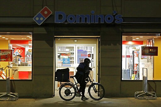 A delivery driver leaves a Domino's Pizza restaurant in downtown Seattle on a bike, Sunday, March 15, 2020. Washington Gov. Jay Inslee said Sunday night that he would order all bars, restaurants, entertainment and recreation facilities in the state to temporarily close to fight the spread of the COVID-19 coronavirus. Inslee said that restaurants could continue take-out and delivery services. (AP Photo/Ted S. Warren)