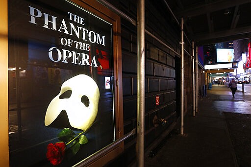 A poster advertising &quot;The Phantom of the Opera&quot; is shown on the shuttered Majestic Theatre on a nearly deserted side street near Times Square, Thursday, March 12, 2020, in New York, after New York Gov. Andrew Cuomo banned gatherings of more than 500 people amid a rise in coronavirus cases. The ban for Broadway theaters started Thursday and will be in effect through April 12, according to a statement from the Broadway League, an organization of theater owners and producers. (AP Photo/Kathy Willens)