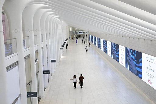 A corridor in the World Trade Center's transportation hub is sparsely occupied, Monday, March 16, 2020 in New York. Millions of Americans have begun their work weeks holed up at home, as the coronavirus pandemic means the entire nation's daily routine has shifted in ways never before seen in U.S. history. (AP Photo/Mark Lennihan)