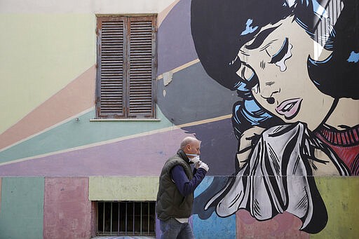 A man adjusts his face mask as he walks past a mural of a crying woman in Rome's Trullo neighborhood, Monday, March 16, 2020. The vast majority of people recover from the new coronavirus. According to the World  Health Organization, most people recover in about two to six weeks, depending on the severity of the illness. (AP Photo/Alessandra Tarantino)