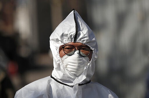 A worker wearing a protective gear prepares to spray disinfectant as a precaution against the new coronavirus in Seoul, South Korea, Monday, March 16, 2020. For most people, the new coronavirus causes only mild or moderate symptoms, such as fever and cough. For some, especially older adults and people with existing health problems, it can cause more severe illness, including pneumonia. (AP Photo/Lee Jin-man)