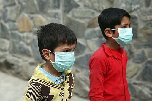 Afghan boys wearing face masks walk at a down town street in Kabul, Afghanistan, Monday, March 16, 2020. For most people, the new coronavirus causes only mild or moderate symptoms. For some it can cause more severe illness. (AP Photo/Rahmat Gul)