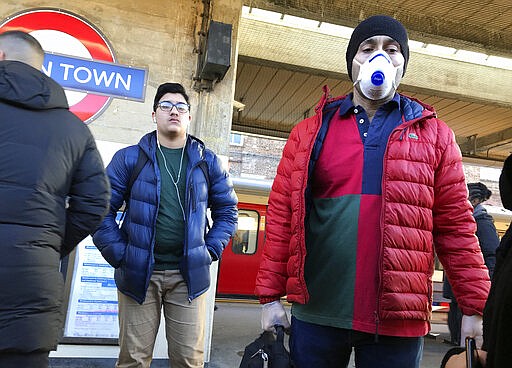 A traveller wears a mask as he gets onto a busy tube in London, Monday, March 16, 2020. For most people, the new coronavirus causes only mild or moderate symptoms, such as fever and cough. For some, especially older adults and people with existing health problems, it can cause more severe illness, including pneumonia. (AP Photo/Kirsty Wigglesworth)