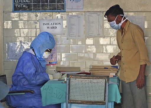 In this Sunday, March 15, 2020, photo, an Indian doctor in a protective suit sits outside an isolation ward for COVIND-19 patients at a Hospital in Hyderabad, India, . For most people, the new coronavirus causes only mild or moderate symptoms. For some, it can cause more severe illness, especially in older adults and people with existing health problems. (AP Photo/Mahesh Kumar A.)