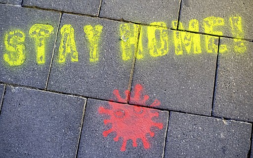 A graffiti consisting of the text &quot;Stay Home&quot; and a symbolic novel coronavirus has been sprayed on the ground in Munich, Germany, Monday March, 16, 2020. Berlin has closed all Bars and pubs because of the corona virus outbreak in Germany. For some, especially older adults and people with existing health problems, it can cause more severe illness, including pneumonia. (Sven Hoppe/dpa via AP)