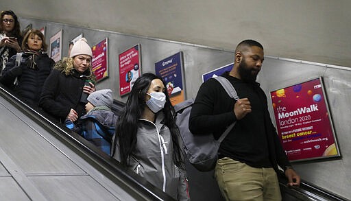 A woman wears a mask as people use an escalator at a station in London, Monday, March 16, 2020. For most people, the new coronavirus causes only mild or moderate symptoms, such as fever and cough. For some, especially older adults and people with existing health problems, it can cause more severe illness, including pneumonia. (AP Photo/Kirsty Wigglesworth)