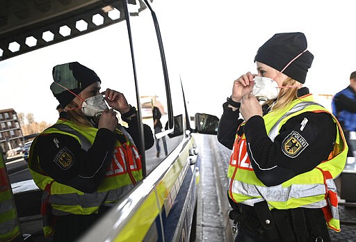 A female federal police officer puts on a breathing mask at the border crossing to Switzerland before an inspection in Weil am Rhein, Monday, march 16, 2020. In the wake of the coronavirus crisis, Germany will introduce comprehensive controls and entry bans at its borders with Switzerland. For most people, the new coronavirus causes only mild or moderate symptoms, such as fever and cough. For some, especially older adults and people with existing health problems, it can cause more severe illness, including pneumonia. (Patrick Seeger/dpa via AP)