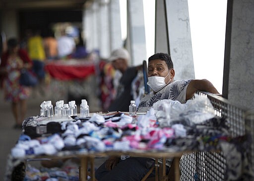 A street vendor sells alcohol and face masks to protect against the spread new coronavirus in a train station in Rio de Janeiro, Brazil, Monday, March 16, 2020. According to the World Health Organization, most people recover in about two to six weeks from the new coronavirus, depending on the severity of the illness. (AP Photo/Silvia Izquierdo)