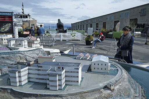 Veronica Phan, of London, looks out at a model of Alcatraz Island near Fisherman's Wharf Monday, March 16, 2020, in San Francisco. Phan and her husband were hoping to visit the island, but because of coronavirus concerns the National Park Service stopped tours until further notice. (AP Photo/Eric Risberg)