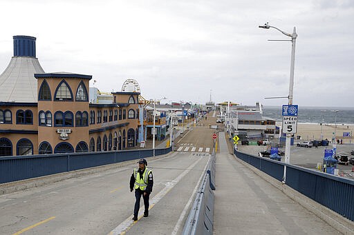 A police officer walks along the exit road at a near-empty Santa Monica Pier following a temporary closure as part of measures to combat the spread of the coronavirus Monday, March 16, 2020, in Los Angeles.For most people, COVID-19 causes only mild or moderate symptoms, such as fever and cough. For some, especially older adults and people with existing health problems, it can cause more severe illness, including pneumonia.  (AP Photo/Marcio Jose Sanchez)