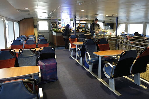 A man fixes his coffee while riding a near empty Golden Gate Ferry from Sausalito Monday, March 16, 2020, to San Francisco. Twelve passengers were riding the boat that normally carries around 200. Millions of California's oldest and youngest residents stayed home Monday as officials took increasingly strident steps to separate people and contain the spread of the coronavirus. (AP Photo/Eric Risberg)