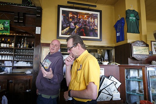 Kevin Jones, right, manager of the Buena Vista Cafe, learns the news that Mayor London Breed is asking city residents to shelter-in-place because of coronavirus concerns Monday, March 16, 2020, in San Francisco. Officials in six San Francisco Bay Area counties issued a shelter-in-place mandate Monday affecting nearly 7 million people, including the city of San Francisco itself. The order says residents must stay inside and venture out only for necessities for three weeks starting Tuesday in a desperate attempt by officials to curb the spread of the novel coronavirus. The cafe is local landmark known for introducing Irish coffee to the U.S. in 1952. (AP Photo/Eric Risberg)