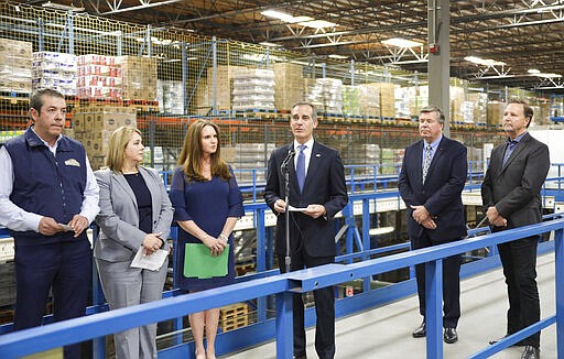 This photo provided by the Office of Los Angeles Mayor Eric Garcetti shows Garcetti, center, joined by grocery executives at a Los Angeles food distribution center for a news conference that was covered only by the mayor's office with no reporters present, and streamed on the Mayor's Facebook page, Monday, March 16, 2020. Garcetti and the executives said there is no reason to panic buy food, that there is plenty of food in the supply chain despite some temporary shortages. (Office of Mayor Eric Garcetti via AP)