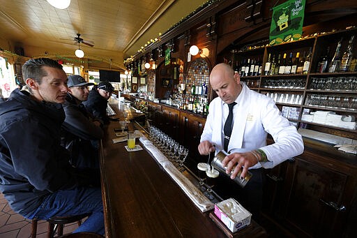 Customers watch as bartender Darcy Parsons makes the signature Irish Coffee at the Buena Vista Cafe near Fisherman's Wharf Monday, March 16, 2020, in San Francisco. Officials in six San Francisco Bay Area counties issued a shelter-in-place mandate Monday affecting nearly 7 million people, including the city of San Francisco itself. The order says residents must stay inside and venture out only for necessities for three weeks starting Tuesday in a desperate attempt by officials to curb the spread of the novel coronavirus. (AP Photo/Eric Risberg)