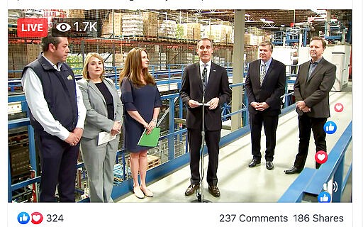 This photo provided by the Office of Mayor Eric Garcetti shows Garcetti, center, joined by grocery executives at a Los Angeles food distribution center for a news conference that was covered only by the mayor's office with no reporters present, and streamed on the Mayor's Facebook page, Monday, March 16, 2020. Garcetti and the executives said there is no reason to panic buy food, that there is plenty of food in the supply chain despite some temporary shortages. (Office of Mayor Eric Garcetti via AP)