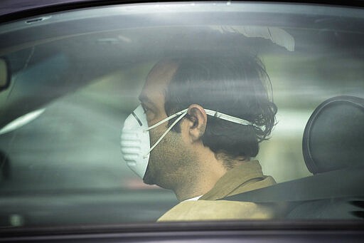 A man wears a mask as he drives along Coldwater Canyon in North Hollywood, Calif. on Monday, March 16, 2020. California has confirmed at least 335 cases of the virus and six deaths. The virus usually causes only mild or moderate symptoms, such as fever and cough, but can be deadly for older people and those with underlying health conditions.  (Sarah Reingewirtz/Pasadena Star-News/via AP)