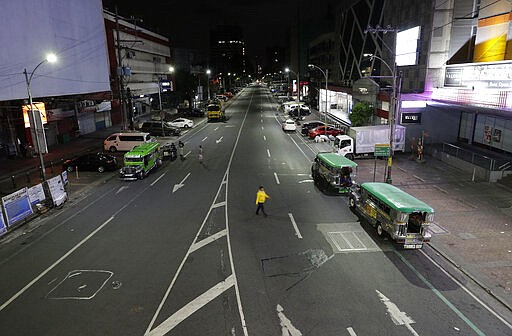 A man crosses an almost empty street shortly past midnight at Quezon city in Manila, Philippines early Tuesday, March 17, 2020 as the government implements an &quot;enhanced community quarantine&quot; that requires millions of people to stay mostly at home in an attempt to contain the new coronavirus. For most people, the new coronavirus causes only mild or moderate symptoms. For some, it can cause more severe illness, especially in older adults and people with existing health problems. (AP Photo/Aaron Favila)