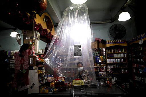 A supermarket cashier waits for costumers behind a makeshift plastic curtain as a precaution against the spread of the new coronavirus, in Buenos Aires, Argentina, Monday, March 16, 2020. For most people, the new coronavirus causes only mild or moderate symptoms, such as fever and cough. For some, especially older adults and people with existing health problems, it can cause more severe illness, including pneumonia. (AP Photo/Natacha Pisarenko)