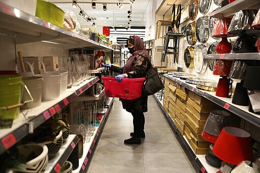 A woman wearing a face mask shops at a store in Bamland shopping mall, in Western Tehran, Iran, Sunday, March 15, 2020. Many people in Tehran shrugged off warnings over the new coronavirus as authorities complained that most people in the capital are not treating the crisis seriously enough. (AP Photo/Vahid Salemi)