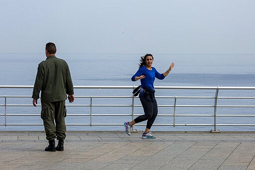 A municipal policeman orders a woman to leave the corniche, or waterfront promenade, along the Mediterranean Sea, in Beirut, Lebanon, Monday, March 16, 2020. For most people, the new coronavirus causes only mild or moderate symptoms, such as fever and cough. For some, especially older adults and people with existing health problems, it can cause more severe illness, including pneumonia. (AP Photo/Hassan Ammar)