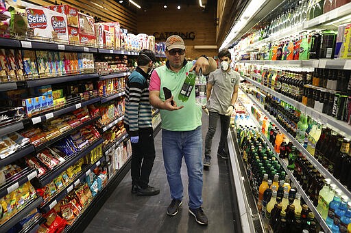 A man shops at a grocery in Bamland shopping mall, in Western Tehran, Iran, Sunday, March 15, 2020. Many people in Tehran shrugged off warnings over the new coronavirus as authorities complained that most people in the capital are not treating the crisis seriously enough. (AP Photo/Vahid Salemi)