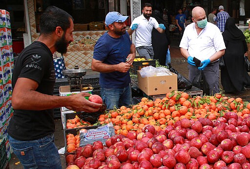 Iraqis buy groceries in downtown Baghdad, Iraq, Monday, March 16, 2020. Iraq announced a weeklong curfew late Sunday. People raced to supermarkets and swiftly emptied shelves, while others stocked up on cooking fuel. The curfew, which is set to begin late Tuesday, includes the suspension of all flights from Baghdad's international airport. (AP Photo/Khalid Mohammed)