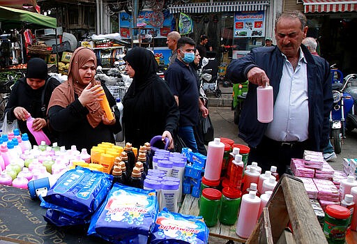 Iraqis buy antiseptics and disinfectants in downtown Baghdad, Iraq, Monday, March 16, 2020. Iraq announced a weeklong curfew late Sunday. People raced to supermarkets and swiftly emptied shelves, while others stocked up on cooking fuel. The curfew, which is set to begin late Tuesday, includes the suspension of all flights from Baghdad's international airport. (AP Photo/Khalid Mohammed)