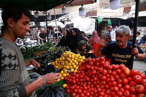 Iraqis buy groceries in downtown Baghdad, Iraq, Monday, March 16, 2020. Iraq announced a weeklong curfew late Sunday. People raced to supermarkets and swiftly emptied shelves, while others stocked up on cooking fuel. The curfew, which is set to begin late Tuesday, includes the suspension of all flights from Baghdad's international airport. (AP Photo/Khalid Mohammed)
