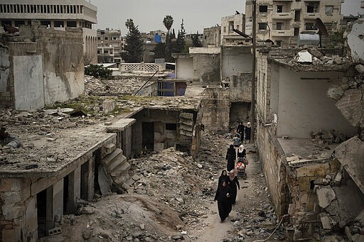 In this Thursday, March 12, 2020 photo, women walk in a neighborhood heavily damaged by airstrikes in Idlib, Syria. Idlib city is the last urban area still under opposition control in Syria, located in a shrinking rebel enclave in the northwestern province of the same name. Syria&#146;s civil war, which entered its 10th year Monday, March 15, 2020, has shrunk in geographical scope -- focusing on this corner of the country -- but the misery wreaked by the conflict has not diminished. (AP Photo/Felipe Dana)