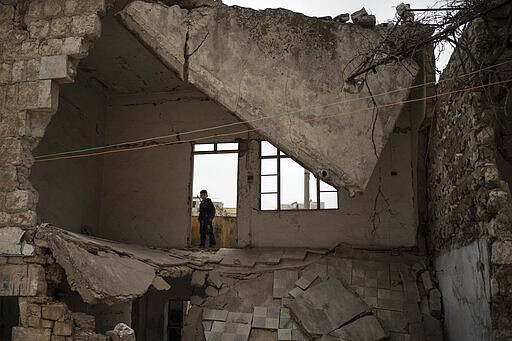 In this Thursday, March 12, 2020 photo, a boy stands inside a house destroyed by an airstrike, in Idlib, Syria. Idlib city is the last urban area still under opposition control in Syria, located in a shrinking rebel enclave in the northwestern province of the same name. Syria&#146;s civil war, which entered its 10th year Monday, March 15, 2020, has shrunk in geographical scope -- focusing on this corner of the country -- but the misery wreaked by the conflict has not diminished. (AP Photo/Felipe Dana)