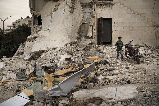 In this Thursday, March 12, 2020 photo, a boy walks out of a heavily damaged building, where he is currently living, in Idlib, Syria. Idlib city is the last urban area still under opposition control in Syria, located in a shrinking rebel enclave in the northwestern province of the same name. Syria&#146;s civil war, which entered its 10th year Monday, March 15, 2020, has shrunk in geographical scope -- focusing on this corner of the country -- but the misery wreaked by the conflict has not diminished. (AP Photo/Felipe Dana)