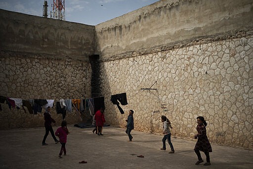 In this Thursday, March 12, 2020 photo, children play inside Idlib's old central prison, now transformed into a camp for people displaced by fighting, in Idlib, Syria. Idlib city is the last urban area still under opposition control in Syria, located in a shrinking rebel enclave in the northwestern province of the same name. Syria&#146;s civil war, which entered its 10th year Monday, March 15, 2020, has shrunk in geographical scope -- focusing on this corner of the country -- but the misery wreaked by the conflict has not diminished. (AP Photo/Felipe Dana)