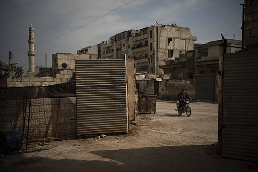 In this Thursday, March 12, 2020 photo, a man rides a motorcycle in Idlib, Syria. Idlib city is the last urban area still under opposition control in Syria, located in a shrinking rebel enclave in the northwestern province of the same name. Syria&#146;s civil war, which entered its 10th year Monday, March 15, 2020, has shrunk in geographical scope -- focusing on this corner of the country -- but the misery wreaked by the conflict has not diminished. (AP Photo/Felipe Dana)