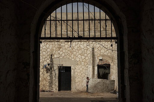 In this Thursday, March 12, 2020 photo, a girl stands inside Idlib's old central prison, now transformed into a camp for people displaced by fighting, in Idli, Syria. Idlib city is the last urban area still under opposition control in Syria, located in a shrinking rebel enclave in the northwestern province of the same name. Syria&#146;s civil war, which entered its 10th year Monday, March 15, 2020, has shrunk in geographical scope -- focusing on this corner of the country -- but the misery wreaked by the conflict has not diminished. (AP Photo/Felipe Dana)