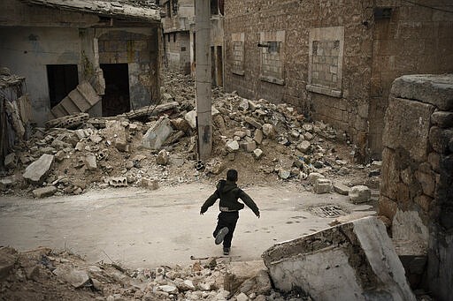 In this Thursday, March 12, 2020 photo, a boy plays in a neighborhood heavily damaged by airstrikes in Idlib, Syria. Idlib city is the last urban area still under opposition control in Syria, located in a shrinking rebel enclave in the northwestern province of the same name. Syria&#146;s civil war, which entered its 10th year Monday, March 15, 2020, has shrunk in geographical scope -- focusing on this corner of the country -- but the misery wreaked by the conflict has not diminished. (AP Photo/Felipe Dana)