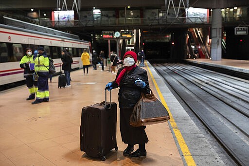 A commuter wearing a face mask and protective gloves waits at the platform of Atocha train station in Madrid, Spain, Monday, March 16, 2020. Streets and roads in and around Madrid were considerably emptier on Monday, the first working day under the new state of emergency lock-down imposed by the Spanish government over the weekend. But a significant slow down in the frequency of commuting trains resulted in considerable crowds gathering in Atocha, one of the capital's main train stations at early morning rush hour, prompting immediate online criticism to authorities for not enforcing the order for people to stay at home. The vast majority of people recover from the new coronavirus. According to the World Health Organization, most people recover in about two to six weeks, depending on the severity of the illness. (AP Photo/Bernat Armangue)