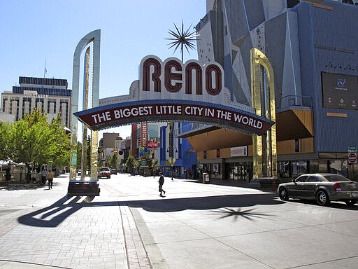 FILE - In this Oct. 11, 2016, file photo, pedestrians pass beneath the Reno arch as traffic passes on Virginia Street in downtown Reno, Nev. All bars, nightclubs, restaurants and gyms will close in Reno by 5 p.m. Friday, March 20, 2020, in an effort to reduce the risk of exposure to coronavirus, Mayor Hillary Schieve announced. Schieve initially included casinos on the closure list late Monday with plans to begin the shutdowns Tuesday morning. But she quickly rescinded that directive and further clarified restaurants can continue carry-out orders and keep drive-through windows open. (AP Photo/Scott Sonner, File)