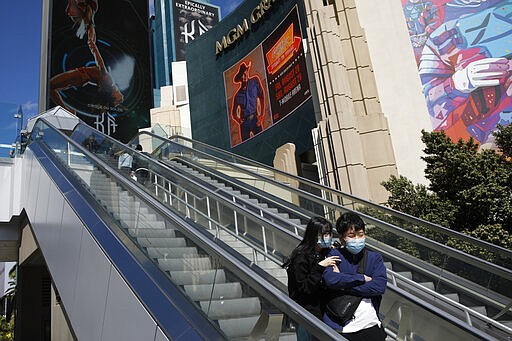 People stand on an escalator in front of the shuttered MGM Grand casino, Tuesday, March 17, 2020, in Las Vegas. MGM Resorts International and Wynn Resorts began closing their properties in Las Vegas on Tuesday in light of the coronavirus outbreak (AP Photo/John Locher)