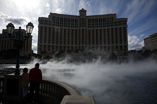 People watch the fountain show at the Bellagio before its closing due to the coronavirus Monday, March 16, 2020, in Las Vegas. MGM Resorts International and Wynn Resorts will close their Las Vegas properties as of March 17 in light of the coronavirus pandemic. (AP Photo/John Locher)