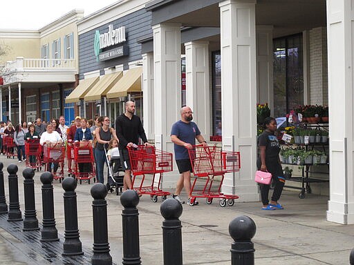 Shoppers seeking to stock up on supplies amid the coronavirus threat line up outside a grocery store in Baton Rouge, La., on Tuesday, March 17, 2020. (AP Photo/Melinda Deslatte)