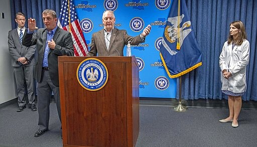 Among other announcements, Gov. John Bel Edwards, center, banned gatherings of 50 or more in another dramatic step to limit the spread of the Coronavirus during a press conference at GOHSEP Monday March 16, 2020, in Baton Rouge, La. Keeping their distance but on hand to answer questions are, Dr. Alex Billioux, asst. state public health officer, left, and Dr. Catherine O'Neal, with Our Lady of the Lake hospital, right. Landon Walker, second from left, signs for the event. He also announced the legislative session is suspended until March 31st. (Bill Feig/The Advocate via AP, Pool)