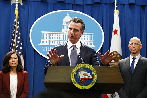 FILE &#151; In this March 12, 2020 file photo, California Gov. Gavin Newsom speaks to reporters about the state's response to the coronavirus during a news conference in Sacramento, Calif. Newsom, a Democrat who leads the nation's most populous state, has won praise from both sides of the aisle for his approach to the coronavirus crisis though he's been less aggressive than some other governors and local leaders. Newsom is accompanied by California Department of Public Heath Director and State Health Officer Dr Sonia Angell, left, and California Health and Human Services Agency Director Dr. Mark Ghaly, right. (AP Photo/Rich Pedroncelli, File)