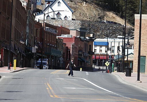 Stephanie Shepherd, a human resources employee of Lodge Casino, heads across the unoccupied main street after casinos were closed to the public in the state's efforts to fend off the spread of coronavirus Tuesday, March 17, 2020, in Black Hawk, Colo. According to the World Health Organization, most people recover in about two to six weeks depending on the severity of the illness. (AP Photo/David Zalubowski)