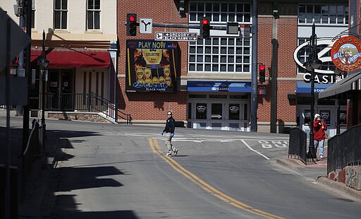 Investigator Jennifer Hotka of the Colorado Gaming Division crosses an empty intersection to check that casinos have been closed to the public in the state's efforts to fend off the spread of coronavirus Tuesday, March 17, 2020, in Black Hawk, Colo. According to the World Health Organization, most people recover in about two to six weeks depending on the severity of the illness. (AP Photo/David Zalubowski)