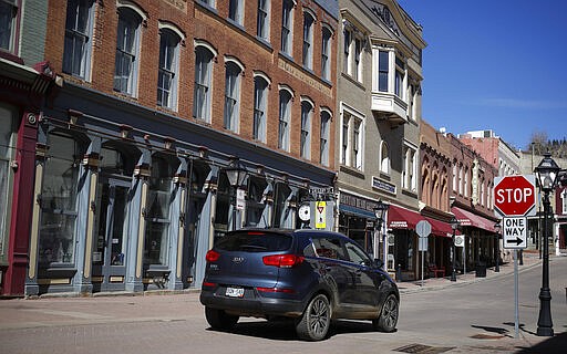 A lone vehicle moves along the main street in Central City, Colo. after casinos were closed to the public in the state's efforts to fend off the spread of coronavirus Tuesday, March 17, 2020, in Central City, Colo. According to the World Health Organization, most people recover in about two to six weeks depending on the severity of the illness. (AP Photo/David Zalubowski)