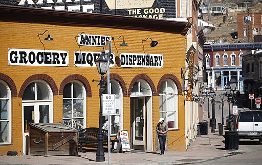 A lone pedestrian walks past one of the few businesses open after casinos have been closed to the public in the state's efforts to fend off the spread of coronavirus Tuesday, March 17, 2020, in Central City, Colo. According to the World Health Organization, most people recover in about two to six weeks depending on the severity of the illness. (AP Photo/David Zalubowski)